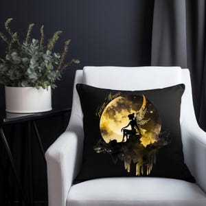 Op de afbeelding: Een zwart kussen met een gouden silhouet van een fee die op een halve maan zit met de tekst "Fairy Magic".