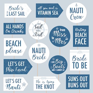 Op de afbeelding: Een verzameling fotohokjes met nautische thema's in wit en marineblauw. De rekwisieten bevatten zinnen als "Bride's Last Sail", "Vitamin Sea" en "Nauti Crew". Ideaal voor een bruiloft of vrijgezellenfeest met strandthema.