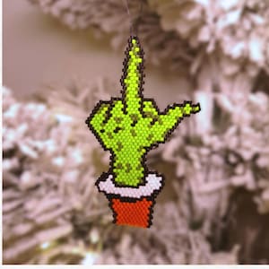 Puede incluir: Adorno de cuentas con la forma de la mano del Grinch haciendo una peineta. La mano verde con contornos negros está en una maceta roja con borde blanco. El texto "GRINCH HAND" está en la parte superior. Hecho con cuentas Miyuki Delica.