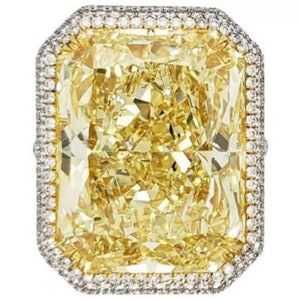 May include: A large, radiant cut, canary yellow diamond ring with a diamond halo setting.