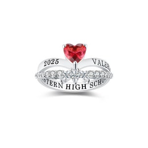 May include: A silver ring with a red heart-shaped stone and clear stones. The ring has the text "VALERIE" and "WESTERN HIGH SCHOOL" engraved on it. The year "2025" is also engraved on the ring.