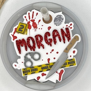 May include: A white round tumbler with a red glitter design that says "MORGAN" with a knife, handcuffs, and crime scene tape.