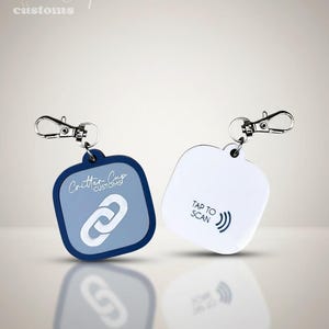 May include: Two keychains with silver clasps. One is square with a blue border and a light blue center with a white chain link graphic and the text "Critter Cup Customs". The other is white with the text "TAP TO SCAN" and a radio wave graphic.