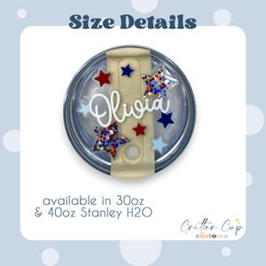 May include: A circular tumbler lid topper featuring the name Olivia in white script, surrounded by red, blue, and light blue stars, including some with holographic glitter. Text states Size Details and available in 30oz & 40oz Stanley H2O.