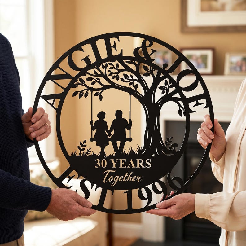 Puede incluir: Un letrero de pared circular de metal negro con un dise&ntilde;o recortado de un &aacute;rbol con una pareja sentada en un columpio. El texto dice ANGIE & JOE, 30 YEARS Together y EST 1996. El dise&ntilde;o est&aacute; enmarcado por un borde circular negro.