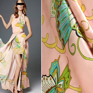 May include: A pink maxi dress with a butterfly print. The dress has a halter neckline and a high slit. The fabric is silky and flowing.