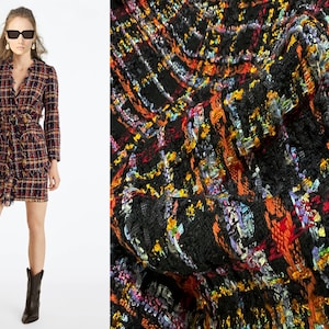 Könnte beinhalten: Ein schwarzes Tweedkleid mit einem bunten Muster in Orange, Gelb, Blau und Rot. Das Kleid hat einen V-Ausschnitt, lange Ärmel und einen Gürtel.