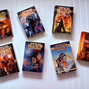 May include: Collection of vintage Star Wars novels with various covers, including "The Truce at Bakura," "Specter of the Past," and "The Courtship of Princess Leia." The books feature character illustrations and the Star Wars logo.