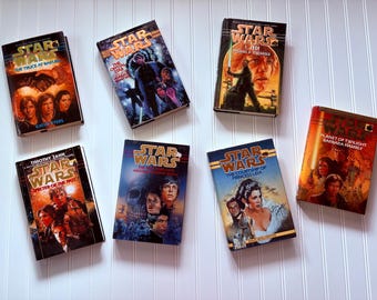 May include: A selection of vintage Star Wars novels, including titles like "The Truce at Bakura" and "Specter of the Past." The book covers display character illustrations and the Star Wars logo, with a variety of colours.