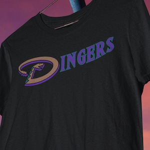 May include: Black t-shirt featuring a purple and brown baseball logo with the text "Dingers" in a teal and purple font.