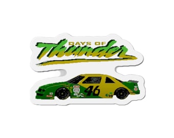 Może przedstawiać: Zielono-żółty samochód wyścigowy z numerem 46 na boku. Samochód znajduje się na białym tle z napisem "Days of Thunder" nad nim.