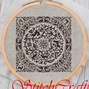 Può includere: Un ricamo a punto croce in bianco e nero con un design circolare con intricati dettagli floreali e figure di animali. Il design è incorniciato in un telaio da ricamo in legno.