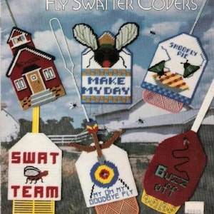 May include: Five colorful fly swatter covers with different designs. The covers feature a schoolhouse, a fly with the text "Make My Day", a pie with the text "Shoofly Pie", a target with the text "My Oh My Goodbye Fly", and a red cover with the text "Buzz Off".