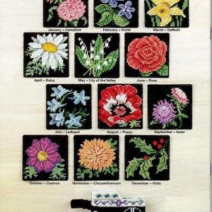 May include: A chart of 12 embroidered flower designs, each representing a different month of the year. The flowers are displayed in a black frame with a white background. The chart is titled "Flower Cart".