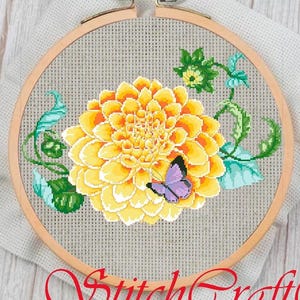 May include: Cross-stitch embroidery of a yellow dahlia flower with a purple butterfly, green leaves, and vines. The embroidery is set in a wooden hoop. The text "StitchCraft" is at the bottom of the image.