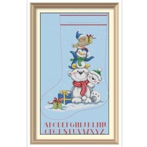 Peut inclure: Broderie au point de croix d'un bas de Noël avec une pile de personnages de dessins animés : un ours polaire, un pingouin et un phoque, tous portant des chapeaux et des écharpes d'hiver. Le bas est bleu clair avec un cadre doré.