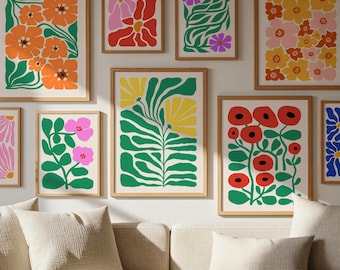 Könnte beinhalten: Eine Galerie-Wand mit neun gerahmten Kunstdrucken, die verschiedene Blumen- und Pflanzenillustrationen in leuchtenden Farben wie Orange, Pink, Rot, Gelb, Grün und Blau zeigen, alle in passenden hellen Holzrahmen.