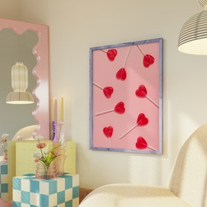 May include: A framed print with a pink background and a pattern of red heart-shaped lollipops on sticks. The lollipops are arranged in a random pattern.