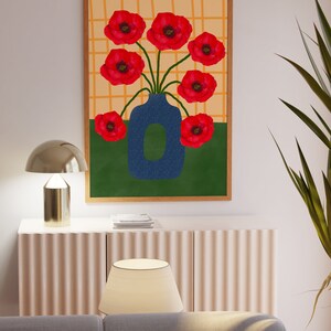 May include: A framed print of a blue vase with red poppy flowers on a yellow and green background.