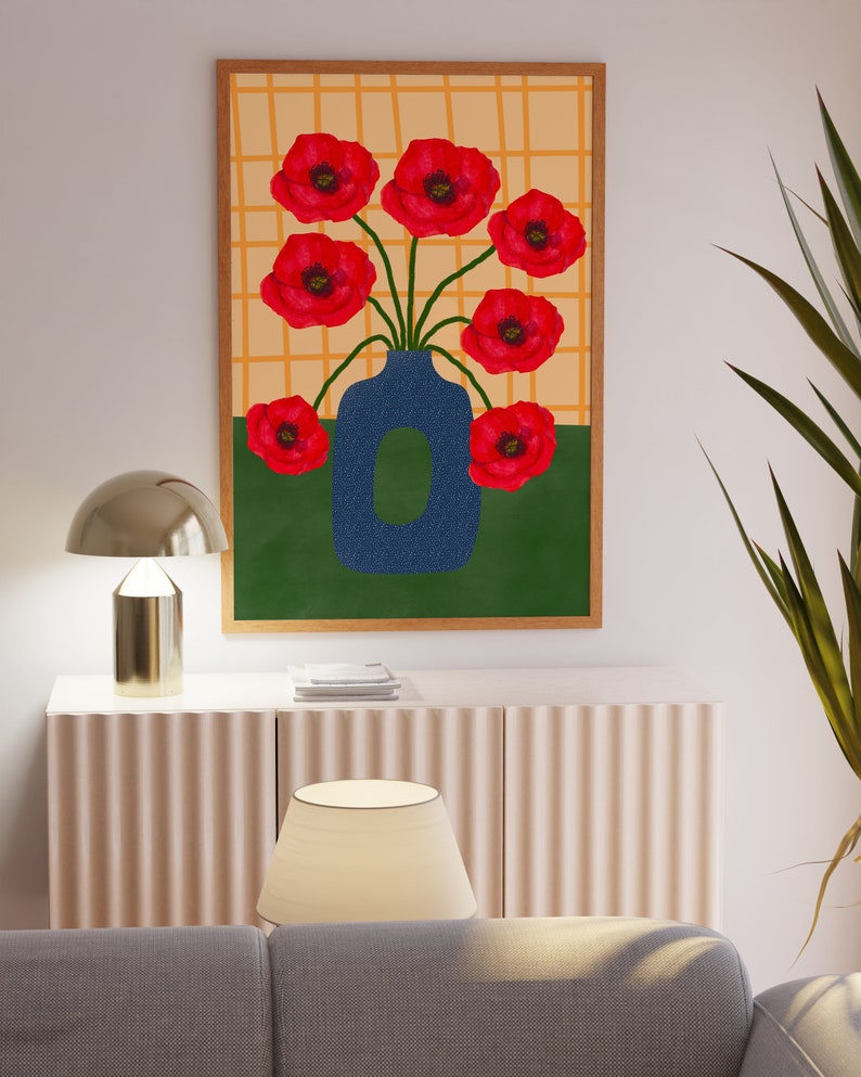 May include: A framed print of a blue vase with red poppy flowers on a yellow and green background.