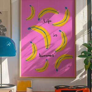 Może przedstawiać: R&oacute;żowy plakat w ramie z ż&oacute;łtym wzorem banan&oacute;w i tekstem "life is bananas".