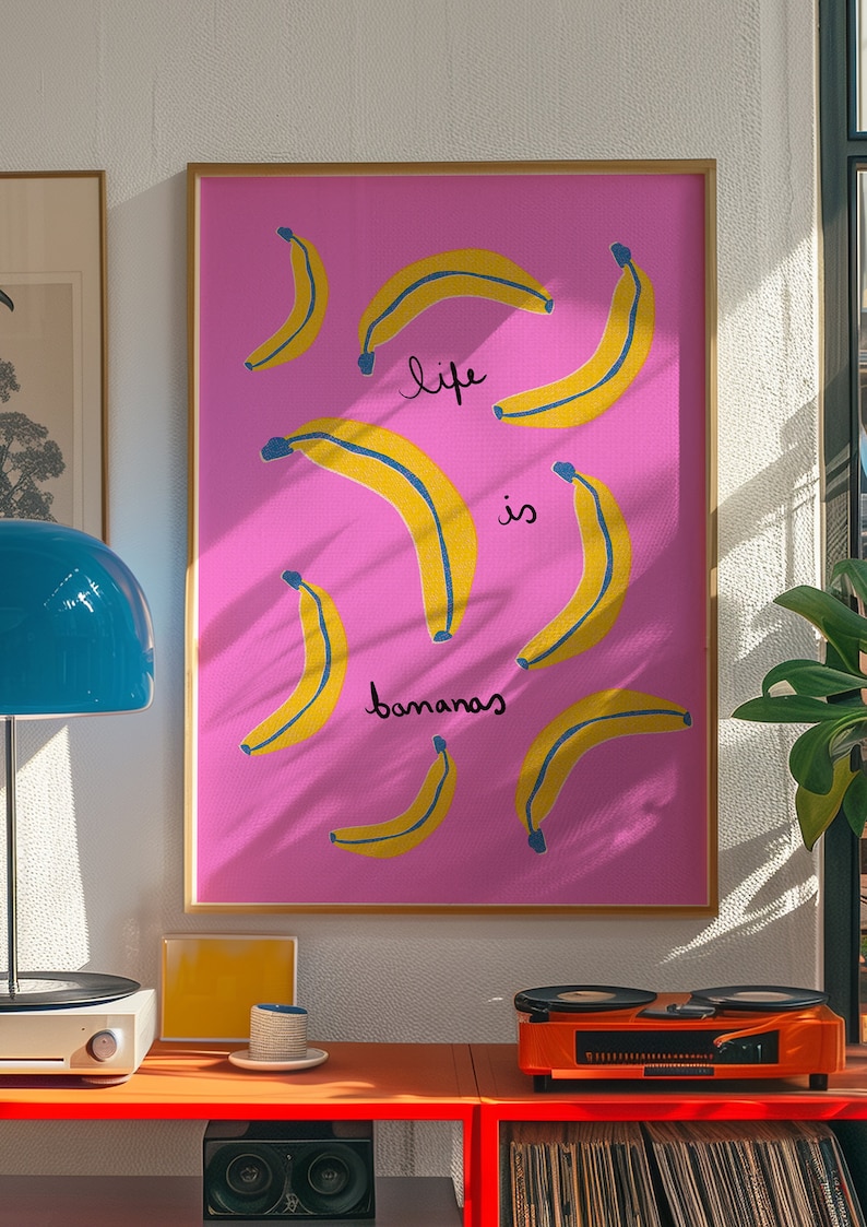 Może przedstawiać: R&oacute;żowy plakat w ramie z ż&oacute;łtym wzorem banan&oacute;w i tekstem "life is bananas".