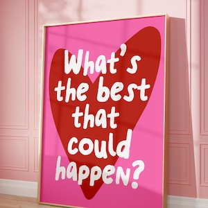 May include: A framed print with a pink background and a red heart shape. The white text reads "What's the best that could happen?" The frame is gold, and the print is displayed on a pink wall.