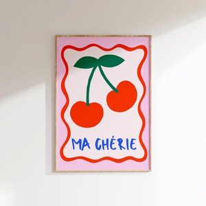 May include: A pink and white framed print with a red and green illustration of two cherries and the text "MA CH&Eacute;RIE" in blue.