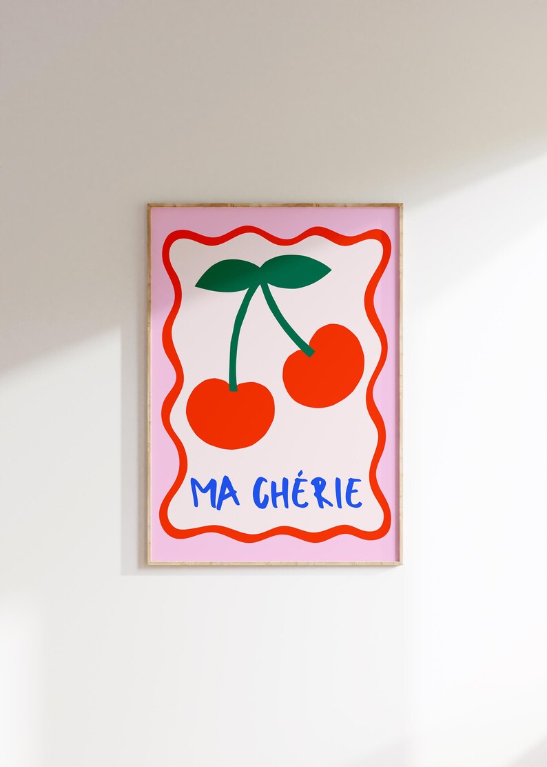 May include: A pink and white framed print with a red and green illustration of two cherries and the text "MA CH&Eacute;RIE" in blue.