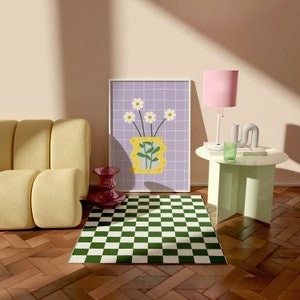 May include: A framed art print showing a yellow vase with white daisies on a purple grid. The room includes a yellow sofa, a green and white checkered rug, a pink lamp, and a small green table.