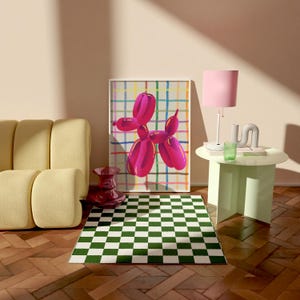 May include: A modern living room scene featuring a framed artwork of a pink balloon dog against a colorful grid background. A green and white checkered rug sits on a wooden floor. A yellow sofa, a pink lamp, and a small table complete the decor.