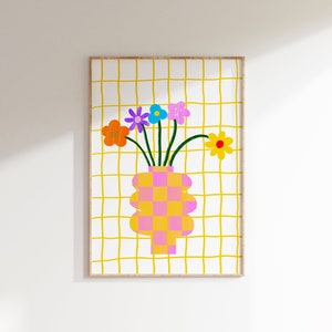 May include: A framed wall art print featuring a checkered pink and yellow vase holding five colorful flowers in orange, purple, blue, pink, and yellow. The background consists of a white surface with a hand-drawn yellow grid pattern throughout.