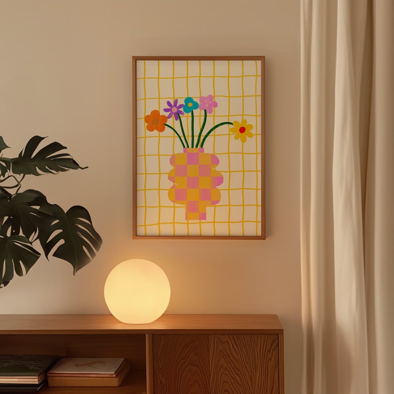 May include: A framed wall art print featuring a checkered pink and orange vase holding a bouquet of colorful flowers, including orange, purple, blue, pink, and yellow blossoms, set against a white background with a yellow grid pattern.