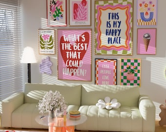 May include: A living room scene featuring a light green sofa, a round glass coffee table with orange legs, and a collection of framed art prints on the wall. The prints have colorful designs and text, including "THIS IS MY HAPPY PLACE" and "WHAT'S THE BEST THAT COULD HAPPEN?"