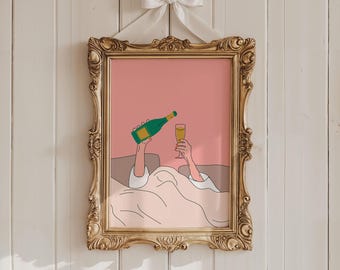 May include: A framed art print featuring a champagne bottle pouring into a glass. The illustration is set against a pink background, within a gold ornate frame, and is suspended by a white ribbon bow.