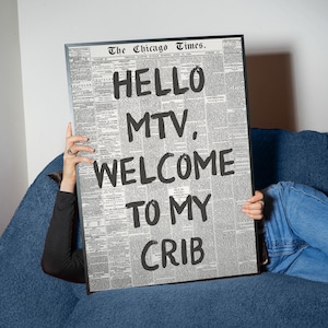 May include: A rectangular framed print featuring a vintage newspaper page from The Chicago Times. The text HELLO MTV, WELCOME TO MY CRIB is printed in large, bold, black sans-serif letters over the columns of small, dense, black and white newsprint.