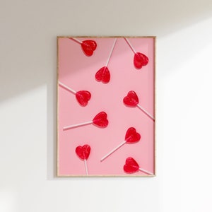 May include: A framed print with a pink background and multiple red heart-shaped lollipops on sticks.