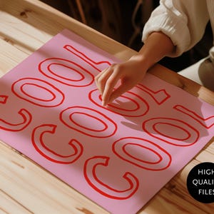 May include: A pink sheet of paper with the word "COOL" in red, outlined letters. The paper is on a wooden surface. A hand is touching the paper. A black circle with the words "HIGH QUALITY FILES" is in the bottom right corner.