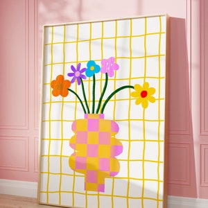 May include: A framed wall art print featuring a white background with a yellow grid pattern. A vase with a pink and yellow checkerboard design holds five colorful flowers in orange, purple, blue, pink, and yellow with green stems.