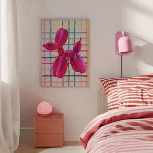 May include: A framed artwork featuring a magenta balloon dog against a colorful grid background. The artwork hangs above a nightstand and bed with pink and white striped bedding. A pink lamp and wall sconce add to the room's decor.