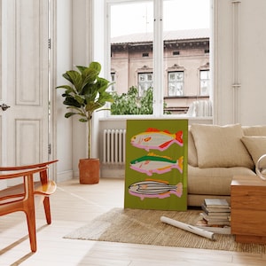 Puede incluir: Una colorida impresi&oacute;n art&iacute;stica de peces sobre un fondo verde. La obra presenta tres peces estilizados con detalles rojos, amarillos, rosas y negros. La impresi&oacute;n se exhibe en una habitaci&oacute;n luminosa con una ventana y una planta en maceta.