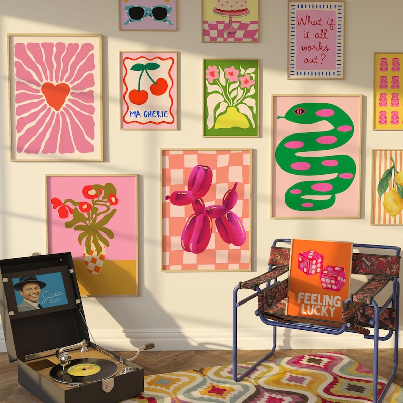 May include: A selection of framed art prints with a retro theme, featuring a pink heart, cherries, a balloon dog, and a green snake. A vintage record player and a chair with a "Feeling Lucky" cushion complete the room's decor.