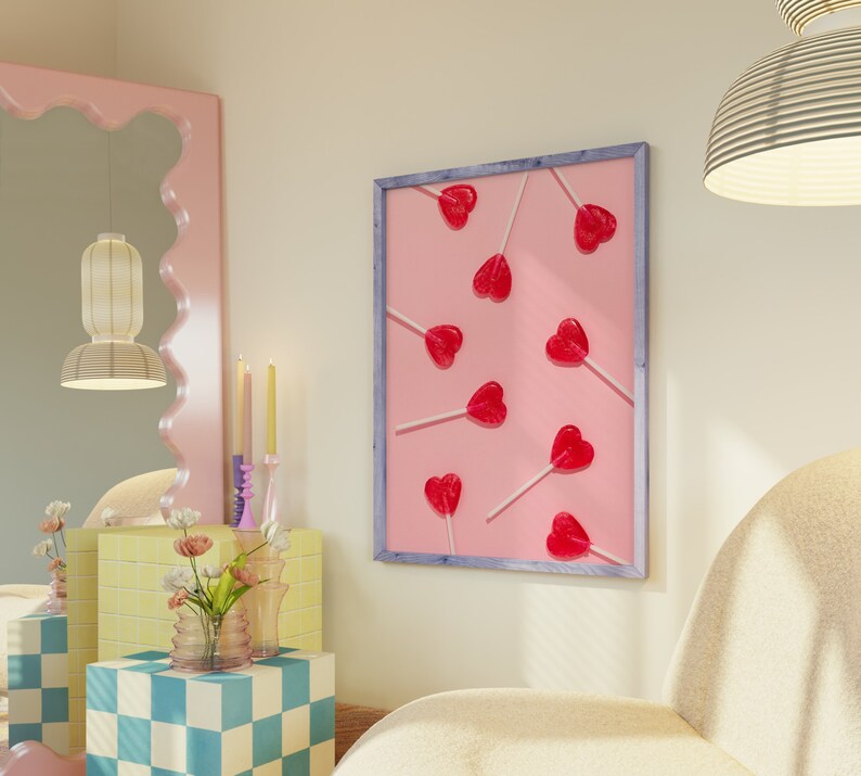 May include: A framed print with a pink background and a pattern of red heart-shaped lollipops on sticks. The lollipops are arranged in a random pattern.