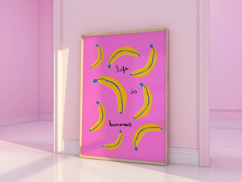 Może przedstawiać: R&oacute;żowy plakat w ramie z tekstem "life is bananas" w czarnych i niebieskich literach. Plakat przedstawia wz&oacute;r ż&oacute;łtych banan&oacute;w na r&oacute;żowym tle.