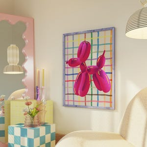 May include: A framed artwork featuring a vibrant pink balloon dog against a colorful plaid background. The artwork is displayed on a cream-colored wall, adding a pop of color to the room. The artwork is framed in a light blue frame.
