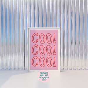 May include: A framed pink print with the word "COOL" repeated three times in red. The print is in a white frame and has a small pink circle with text at the bottom that reads "PRINTABLE WALL ART (not a physical item)".