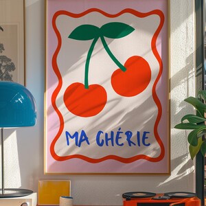 May include: A pink and white framed print with a graphic of two red cherries with green stems and leaves. The text "MA CH&Eacute;RIE" is written in blue below the cherries.