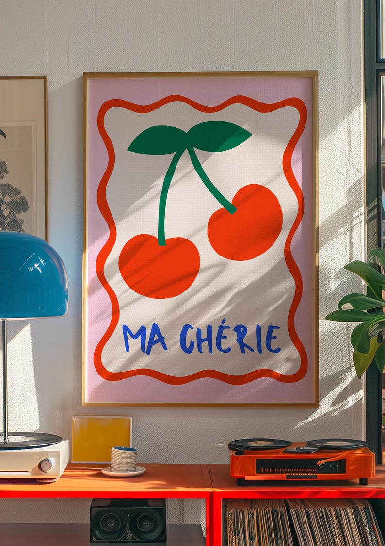 May include: A pink and white framed print with a graphic of two red cherries with green stems and leaves. The text "MA CH&Eacute;RIE" is written in blue below the cherries.
