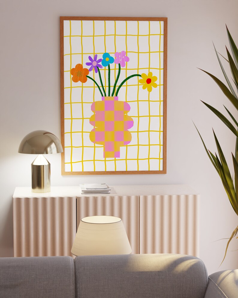 May include: A rectangular framed wall art print featuring a white background with a yellow grid pattern. The central illustration depicts a pink and orange checkered vase holding a bouquet of colorful flowers in orange, purple, blue, and yellow.