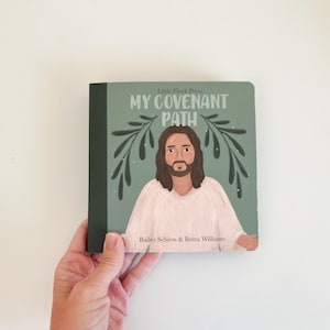 Może przedstawiać: Książka zatytułowana "My Covenant Path" z zieloną okładką przedstawiającą ilustrację mężczyzny z długimi brązowymi włosami i brodą. Książka ma ciemnozielony grzbiet i jest trzymana przez dłoń.